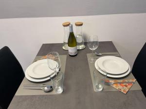 een tafel met borden en glazen en een fles wijn bij Tolles Studio im Zentrum von Rapperswil in Rapperswil-Jona