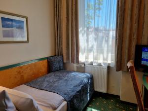 a small bedroom with a bed and a window at myMINGA4 - Hotel & serviced Apartments in Munich