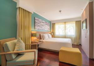 um quarto de hotel com uma cama e uma cadeira em Radisson Resort and Suites Phuket em Praia de Kamala