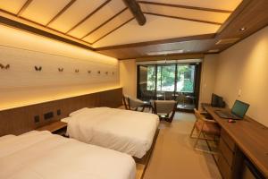 Zimmer mit 2 Betten und einem Schreibtisch mit einem Laptop in der Unterkunft Rankeisou in Sanjo