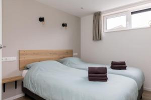 2 Betten in einem Zimmer mit weißen Wänden und einem Fenster in der Unterkunft Vakantiehuis Eikzicht gelegen aan het bos in Elsloo