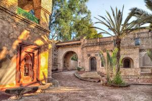 um antigo edifício de pedra com um pátio com uma palmeira em Hivernage Founty em Agadir