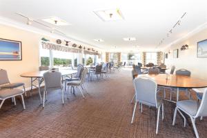 a dining room with tables and chairs and windows at Dune Crest Hotel in North Truro