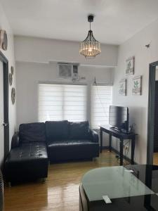 a living room with a black couch and a table at 2 Bedroom Condo Unit in Manila