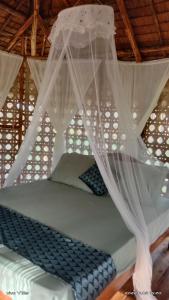 a bed with mosquito netting on top of it at Prince John beachfront cottages and Restaurant in San Vicente
