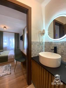 a bathroom with a tub and a bed and a mirror at Regina Munților Spa&Confort in Moieciu de Sus