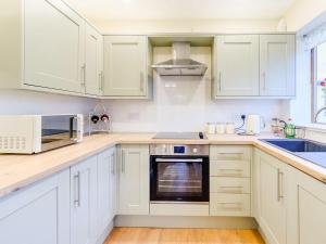 uma cozinha com armários brancos e um forno com placa de fogão em Hayloft- Uk31532 em Goxhill