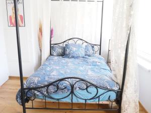 a black iron bed with blue sheets and pillows at Les Halles : Studio Cosy et Moderne in Strasbourg