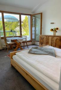 1 dormitorio con cama, mesa y ventanas en Casa Las Caglias, en Flims