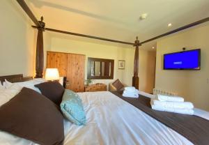 a bedroom with a large bed with a tv on the wall at Lune Cottage nestled between Lake District and Yorkshire Dales in Tebay
