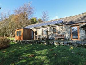 uma casa de pedra com painéis solares em cima em Puidrac Cottage em Lochearnhead