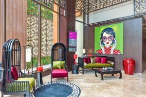 a lobby with chairs and a painting of a woman at Ashley Tang Menteng Jakarta in Jakarta