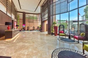 a lobby with chairs and tables and windows at Ashley Tang Menteng Jakarta in Jakarta