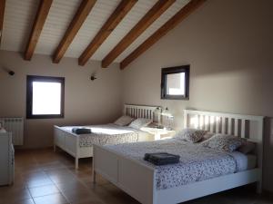 1 dormitorio con 2 camas, mesa y 2 ventanas en El Niu de l'Estany en Ivars d'Urgell