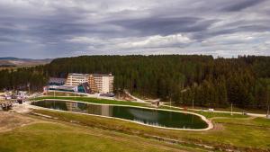 a large pool of water in a field with a building at Hotel Borovi Forest Resort & Spa in Sjenica