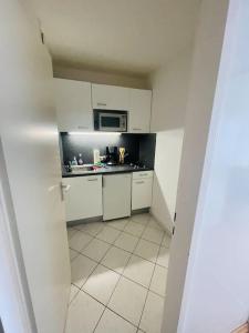 a small kitchen with white cabinets and a microwave at Sunrise Studio für 2-3 Personen in Munich