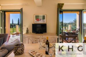 a living room with a television and a table with wine glasses at Villa Elaionas 1 Experiencing nature's tranquility! in Svoronata