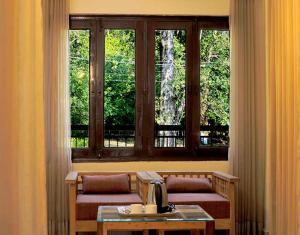 拉姆納格爾的住宿－Hotel Holiday Highlights，一间设有两张长椅和一张桌子及窗户的房间