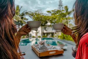 two women sitting at a table with cups in their hands at Villa Sarakkuwa in Pamunugama