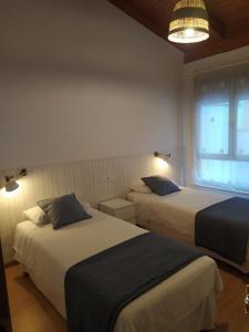 a hotel room with two beds and a window at Adosado de María - Para 4 pax en Posada de Llanes in Llanes