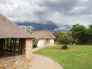 a house with a thatched roof and a walkway at Stone Hounds Lodge in Magaliesburg