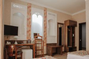 una sala de estar con TV y escritorio y una habitación con en Omar Khayyam Hotel, en Bukhara