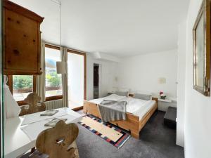 1 dormitorio con cama, escritorio y ventana en Casa Las Caglias, en Flims