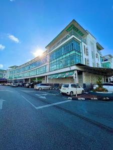 un gran edificio con coches estacionados en un estacionamiento en New World Express Motel, en Bintulu