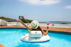 a woman is sitting on an inflatable ring in a pool at The Farmhouse Hotel in Langebaan