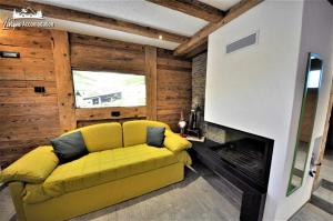 a yellow couch in a living room with a fireplace at Mountain Chalet Scoiattolo in Livigno