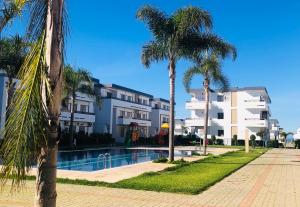 una piscina con palmeras frente a un edificio en Marbella Beach location pour famille 2 chambres en Minaret de Mansuria