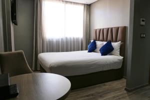 una camera da letto con un letto con cuscini blu e una finestra di Le 22 Appart'Hotel a Casablanca