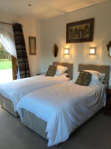 two beds in a bedroom with white sheets at Dalmunach House in Aberlour