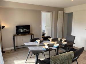 ein Wohnzimmer mit einem Tisch, Stühlen und einem TV in der Unterkunft Appartement Le Lauzet in La Roche-de-Rame