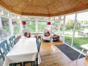 a conservatory with two tables and chairs and windows at Teach Teolai in Carraroe