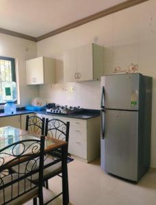 a kitchen with a refrigerator and a table and chairs at Goa Homeland 3 double bed Calangute in Calangute