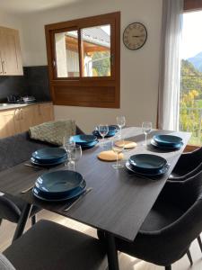 einen Esstisch mit Tellern, Gläsern und einer Uhr in der Unterkunft Appartement Le Lauzet in La Roche-de-Rame