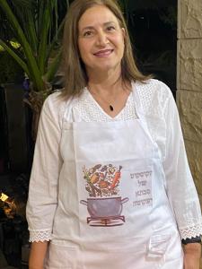 Una donna con una camicia bianca e una pentola di cibo di בין הר למעיין a Kefar Tavor