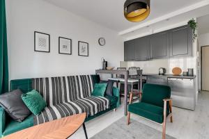 a living room with a green couch and a kitchen at Albatross Tower - apartament w centrum Przymorza by Grand Apartments in Gdańsk