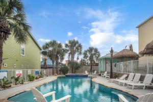 a swimming pool with lounge chairs and palm trees at Sandy Starfish in Port Aransas