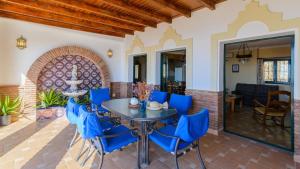 a patio with a table and blue chairs at Villa el Pedregal Frigiliana by Ruralidays in Frigiliana
