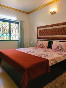 a bedroom with a bed with a red blanket and a window at Goa Homeland 3 double bed Calangute in Calangute