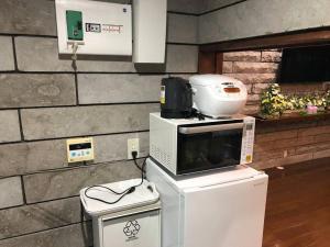 a microwave sitting on top of a refrigerator at 那須町湯本の那須御用邸近くのログハウス in Nasu-yumoto