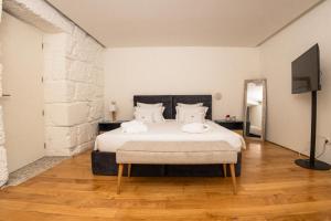 Quinta da Corredoura, Hotel Rural في غيمارايش: غرفة نوم فيها سرير وتلفزيون