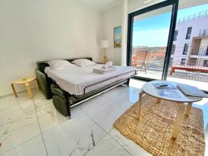 a bedroom with a bed and a table and a balcony at "Cap Riviera" Proche Gare et Centre in Menton