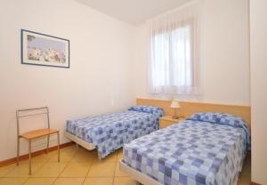 a hotel room with two beds and a window at Villaggio Orchidea in Bibione