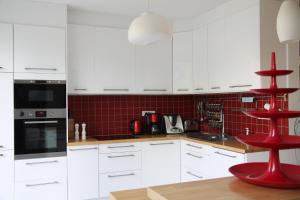 a kitchen with white cabinets and a red stool at Superbe maison avec jardin magnifique! in Schiltigheim