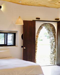 1 dormitorio con un arco de piedra y 1 cama en 滿丘石頭屋ManChill, en Manzhou