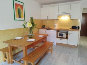 une cuisine avec une table en bois et un vase de fleurs dans l'établissement Appartement T2 cabine pour 8 pers, ski aux pieds, bien équipé, proche commerces et sports - FR-1-262-137, à Forest des Baniols