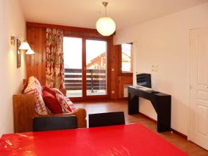ein Wohnzimmer mit einem roten Tisch und einem TV in der Unterkunft Appartement Les Orres, 2 pièces, 4 personnes - FR-1-322-130 in Les Orres